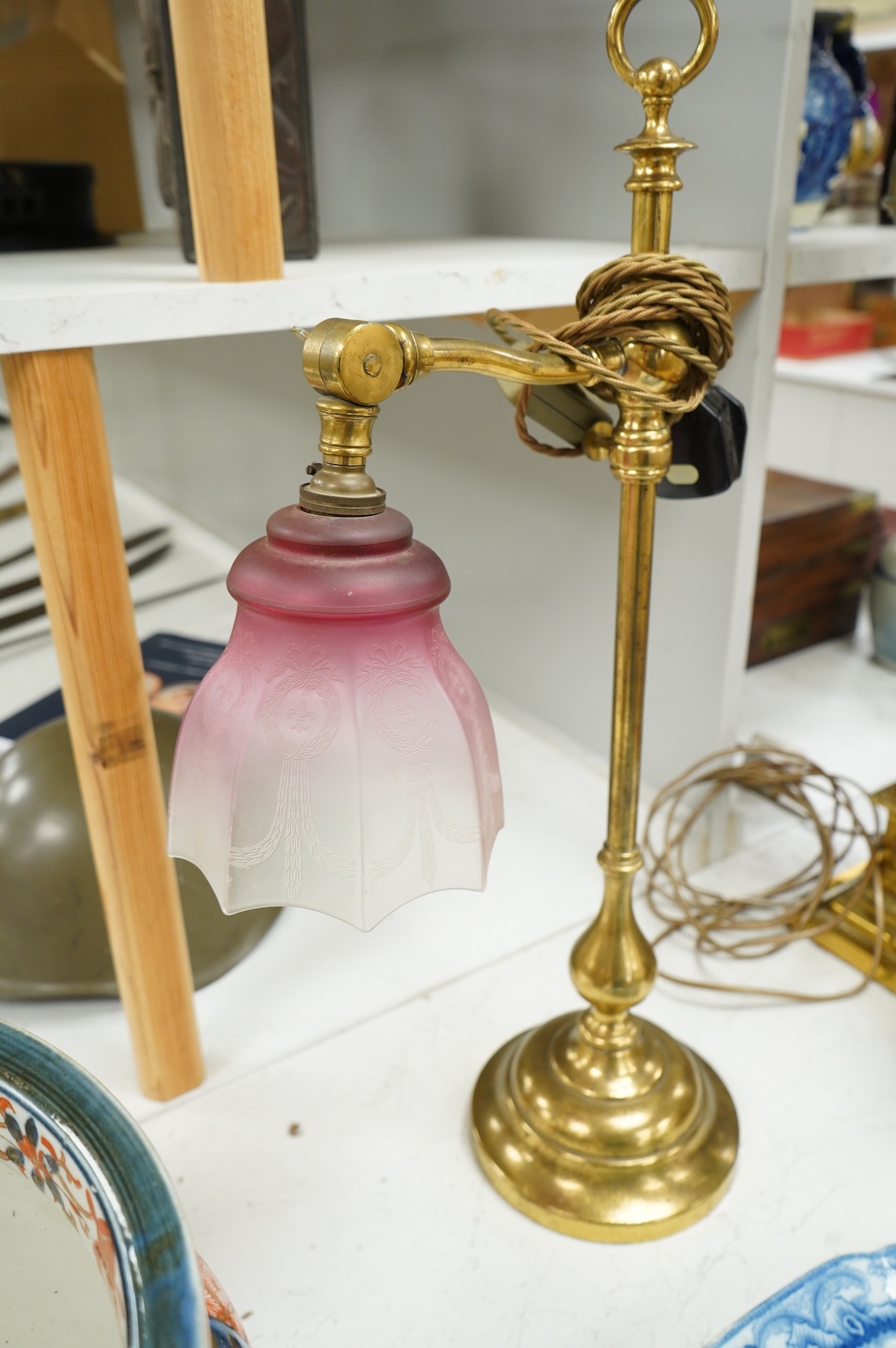 A late Victorian brass desk light with cranberry shade, 59cm